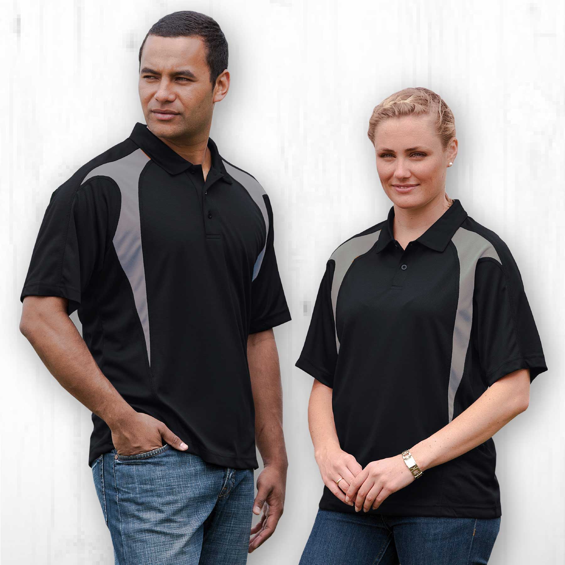 A black polo shirt featuring grey spliced panels, displayed on a male and female model. Includes a branding logo. Dri Gear Spliced Zenith Impact Polo - Image 1