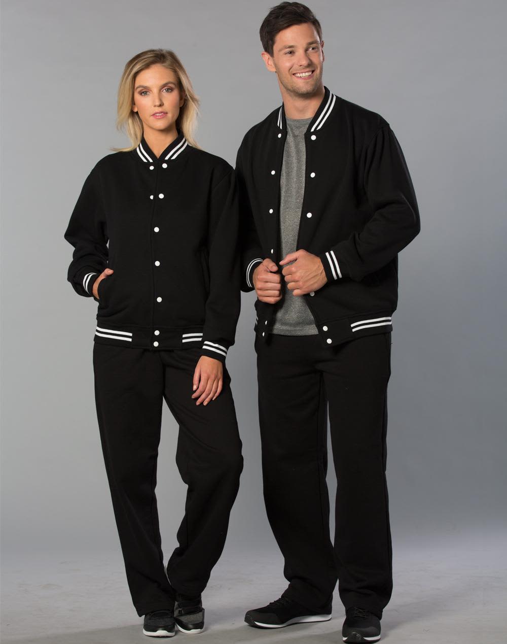 A black fleece varsity jacket with white stripes, worn by a woman and a man, both in matching black pants. Adult's Fleece Varsity Jacket - Image 1