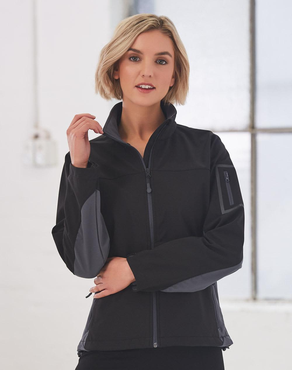 A black softshell jacket with grey accents, featuring a zip front and a side pocket, worn by a model indoors. Ladies' Contrast Softshell Jacket - Image 1