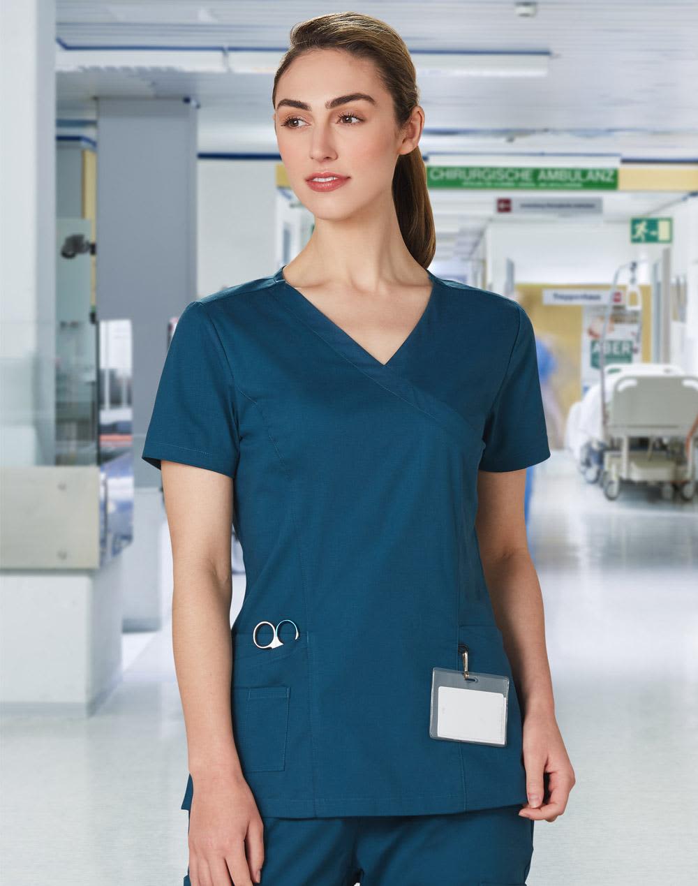 A solid teal short-sleeve scrub top designed for women, featuring a pocket and logo branding. Ladies' Solid Colour S/S Scrub Top - Image 1