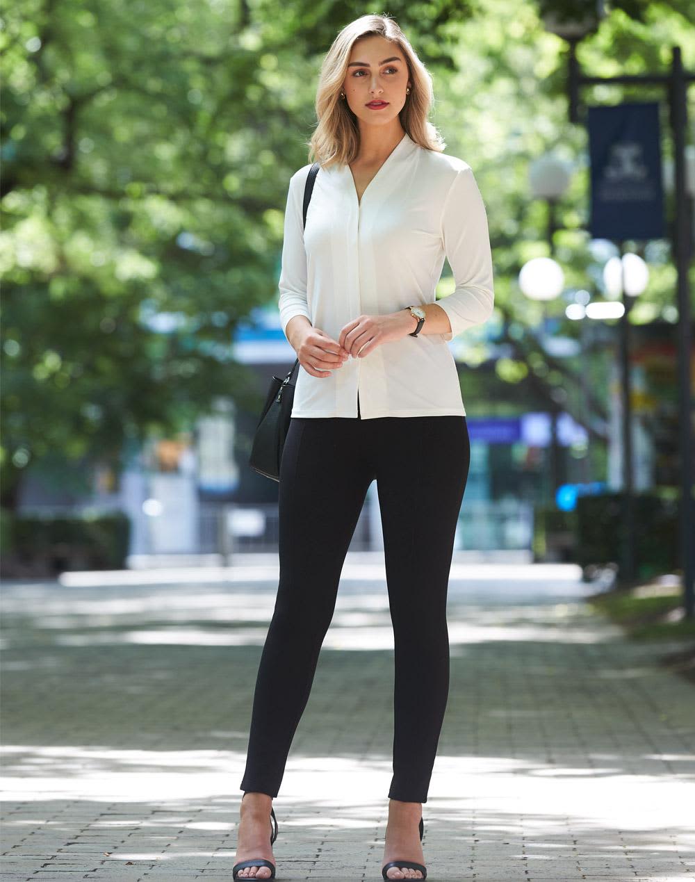 A model stands outdoors wearing black treggings and a white top, complemented by heels and a handbag. Ladies' Ultra Comfort Waist Band Treggings - Image 1
