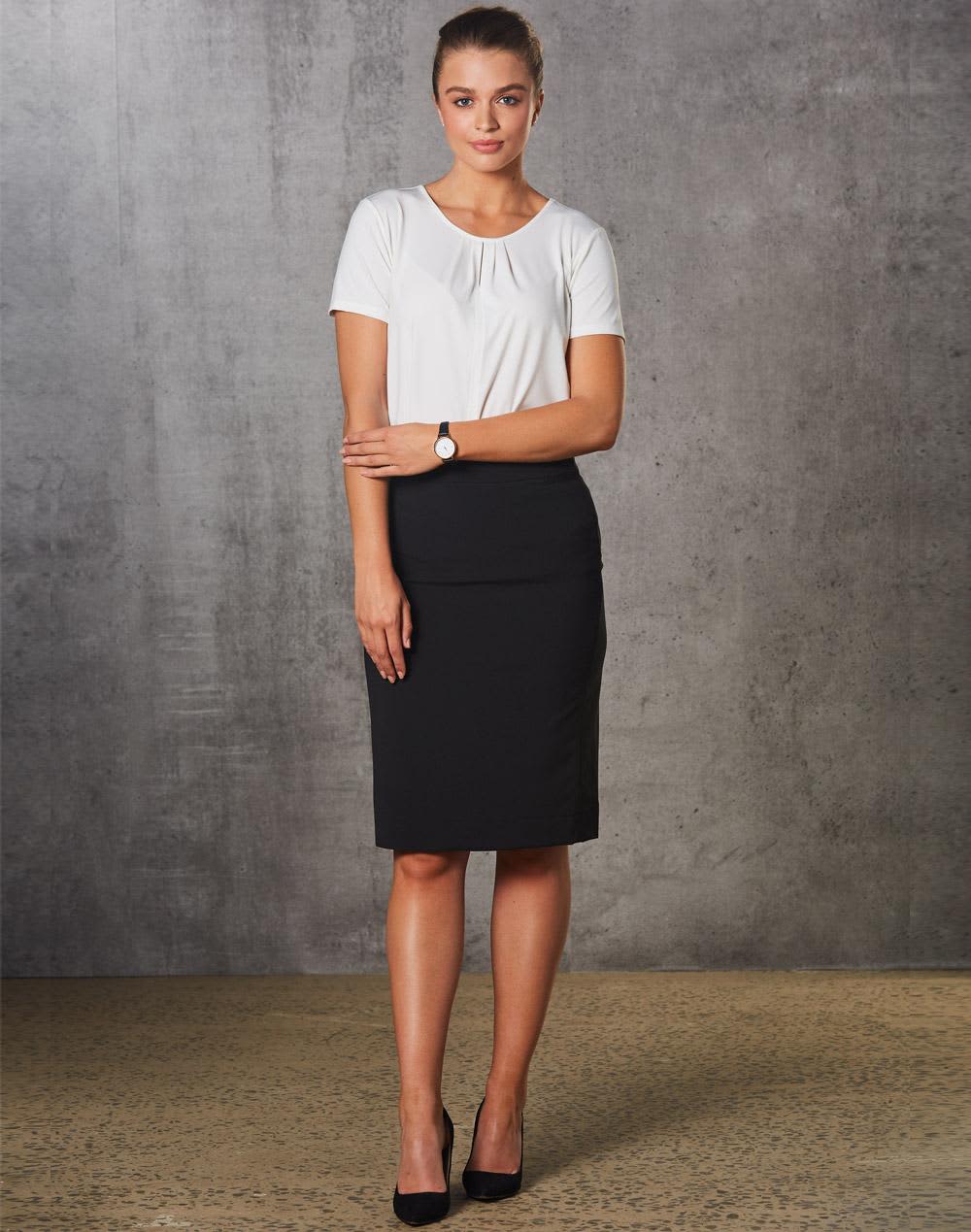 A model wears a black mid-length lined pencil skirt paired with a white top and high heels. The skirt features a subtle stripe pattern. Women's Mid Length Lined Pencil Skirt in Poly/Viscose Stretch Stripe - Image 1