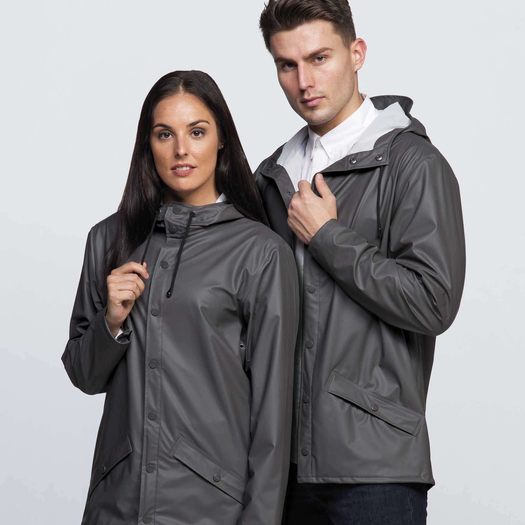 A grey rain jacket worn by a man and woman, featuring a hood and buttons, with a logo present. smpli Optic Jacket - Image 1