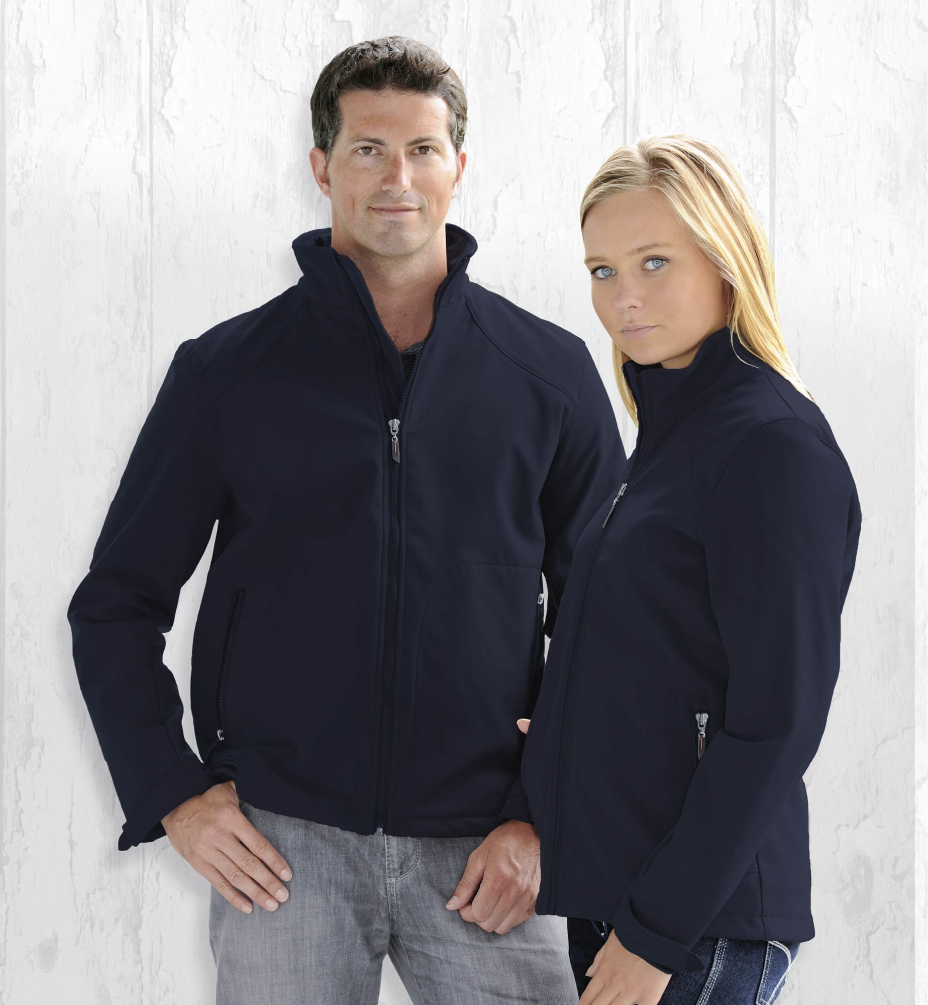 Two models wear the Summit Jacket, a navy soft shell jacket, featuring a logo and front zip. Summit Jacket - Image 1