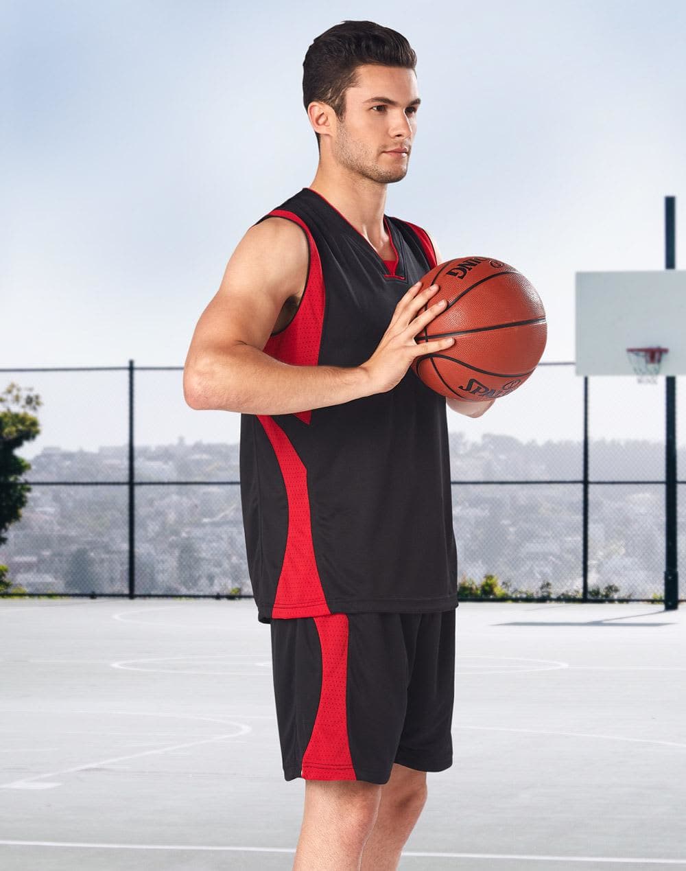 Adults' basketball shorts in black and red, featured with a player holding a basketball on a court. Adults' Basketball Singlet - Image 1