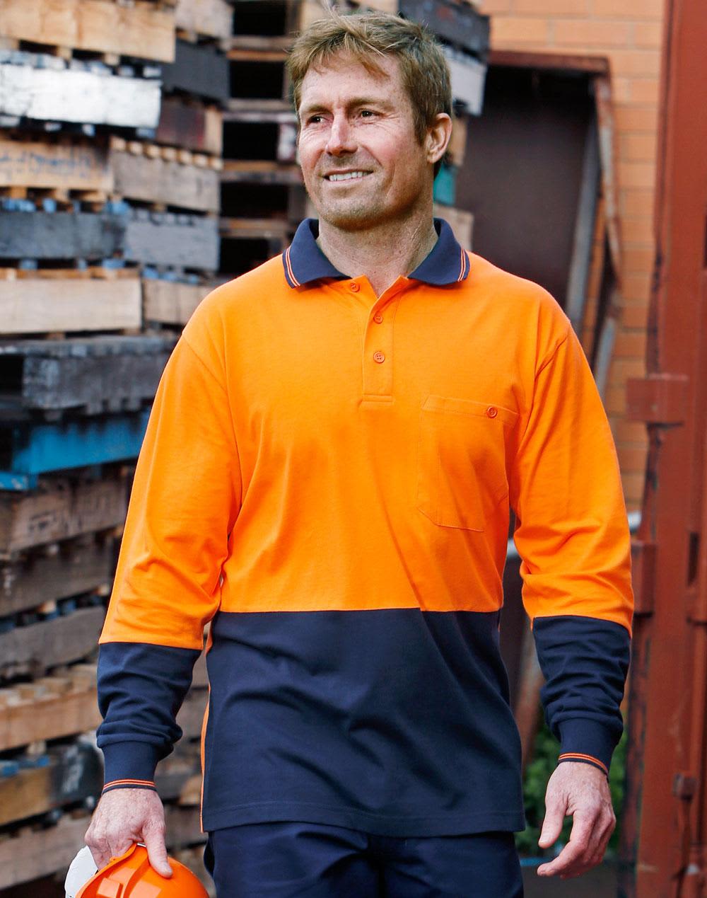 A long-sleeved safety polo in orange and navy, featuring a logo, worn by a man outdoors near wooden pallets. Hi-Vis Cotton Two Tone L/S Safety Polo - Image 1