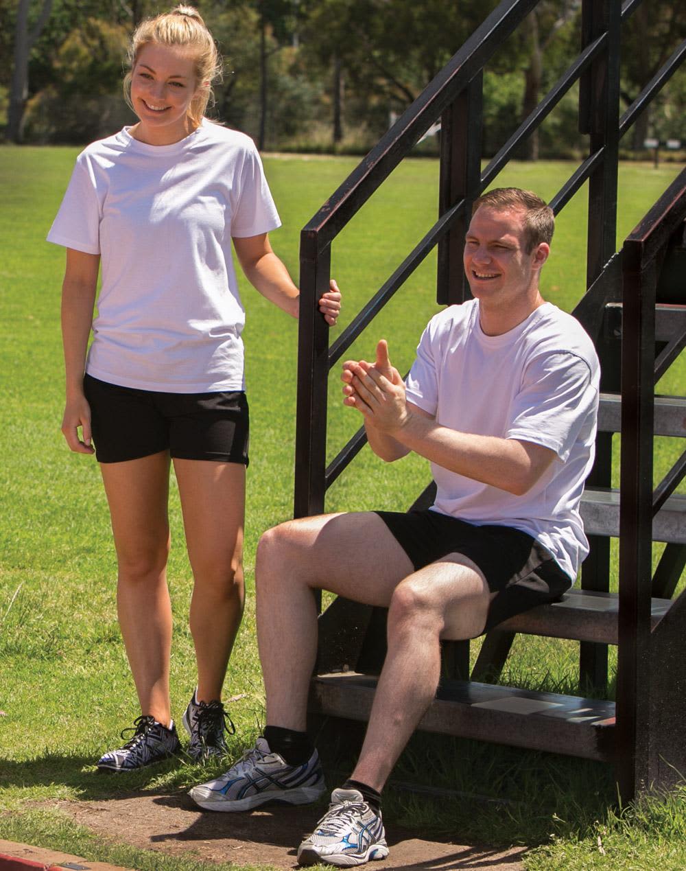 Two individuals wearing white premium t-shirts and black shorts, one sitting on a stair and the other standing nearby. premium tee - Image 1
