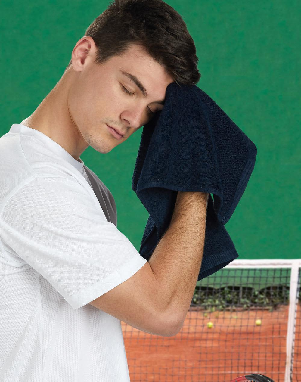 A man in a white shirt wipes his forehead with a dark navy hand towel, set against a green background. Hand towels double side terry. 40x60 cm. - Image 1