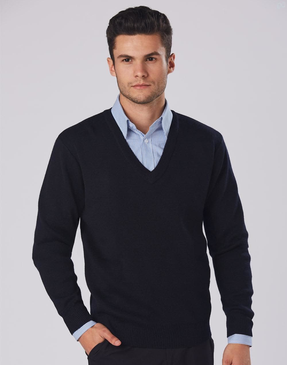 A black V-neck wool and acrylic knit jumper worn over a blue collared shirt, featuring a branding logo. V Neck Wool / Acrylic Knit Jumper - Image 1