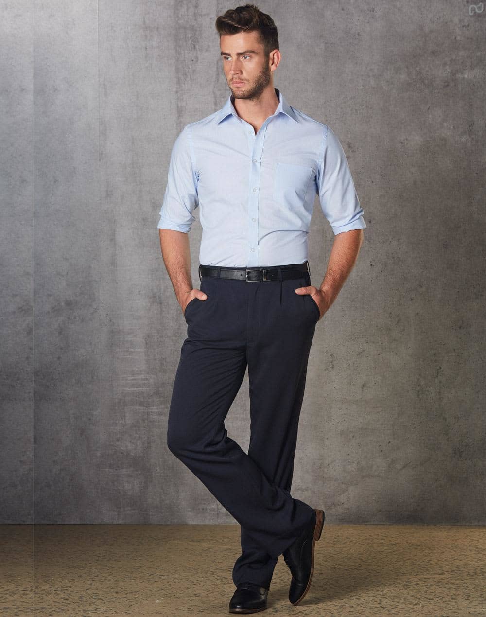 A man in a light blue shirt and black permanent press pants stands with hands in pockets against a grey backdrop. mens permananent press pants reg - Image 1