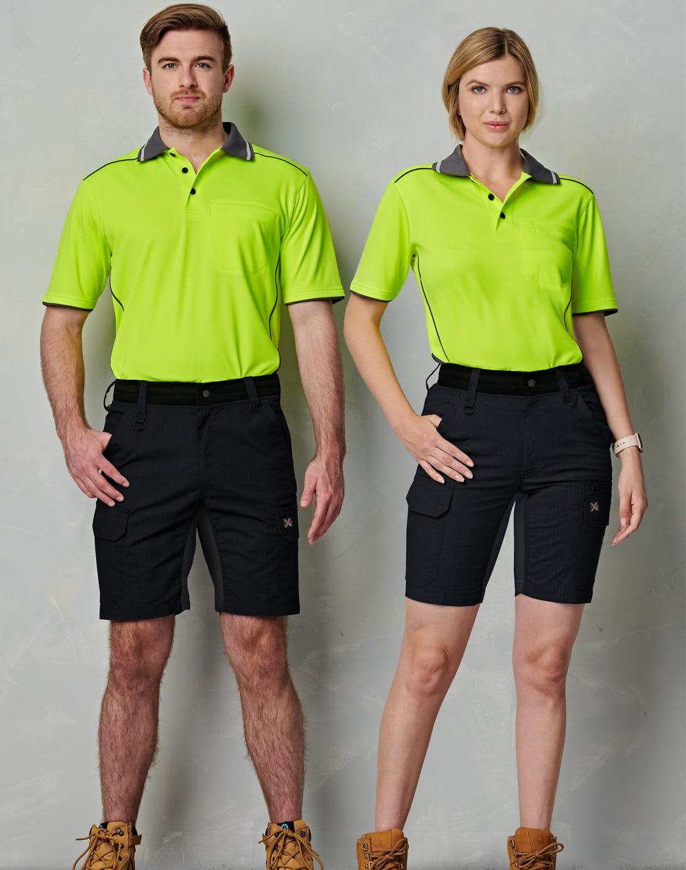 A pair of models wearing bright green polo shirts and black Rip-Stop Poly/Cotton Stretch Work Shorts. Rip-Stop Poly/Cotton Stretch Work Shorts - Image 1
