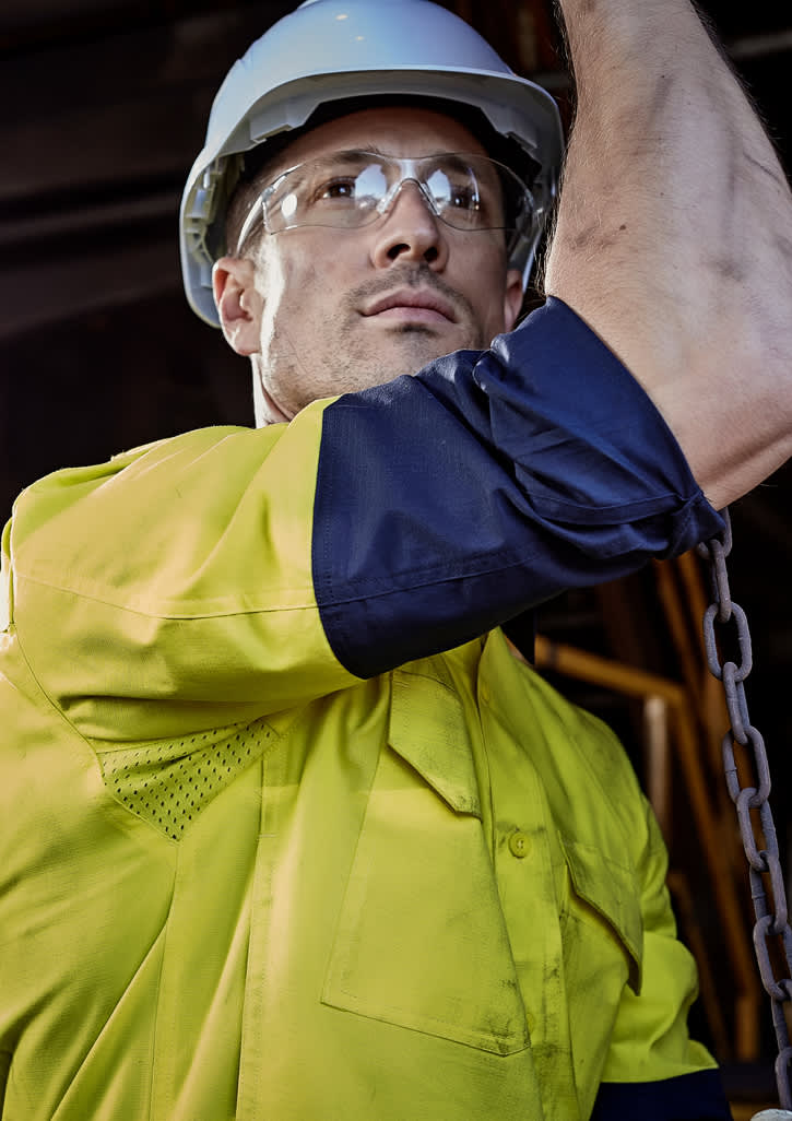 A rugged long sleeve shirt in yellow and navy, featuring reflective elements and a logo, worn by a person in safety gear. Mens Rugged Cooling Hi Vis Long Sleeve Shirt - Image 1