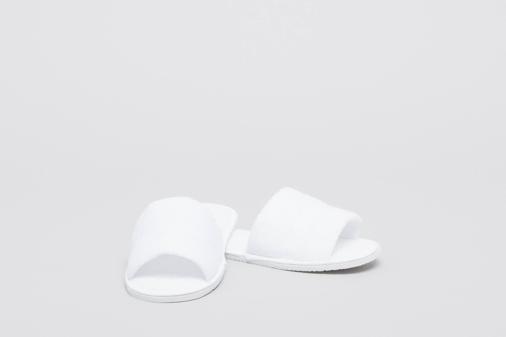 White open-toe spa bathroom slippers with a fluffy texture and flat soles, presented on a plain background. Spa Bathroom Slippers Open Toe - Image 1
