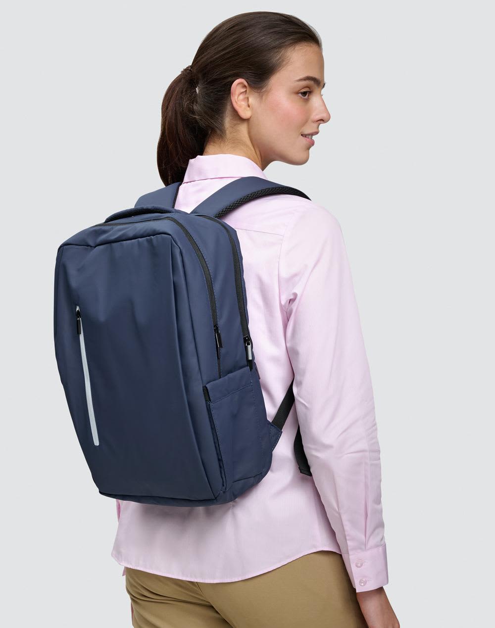 A navy blue backpack with a sleek design is worn on the back of a person, featuring zippers and compartments. Elite PU Backpack - Image 1