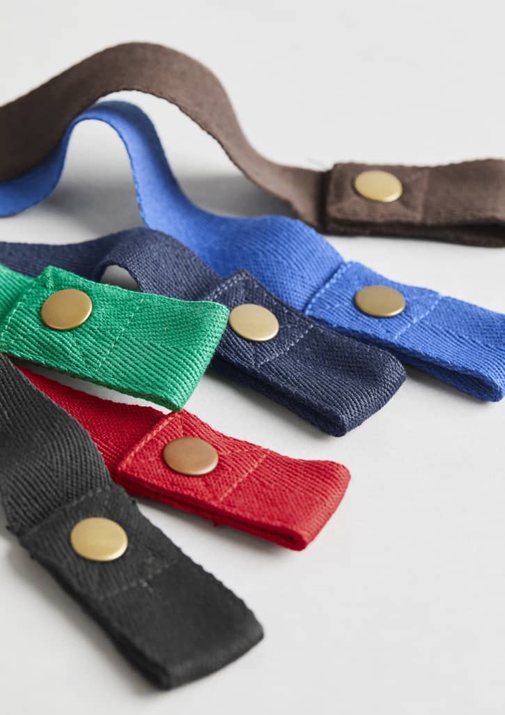 A collection of fabric waist straps in green, red, blue, black, navy, and brown, featuring gold studs and a sturdy design. Urban Waist Straps - Image 1