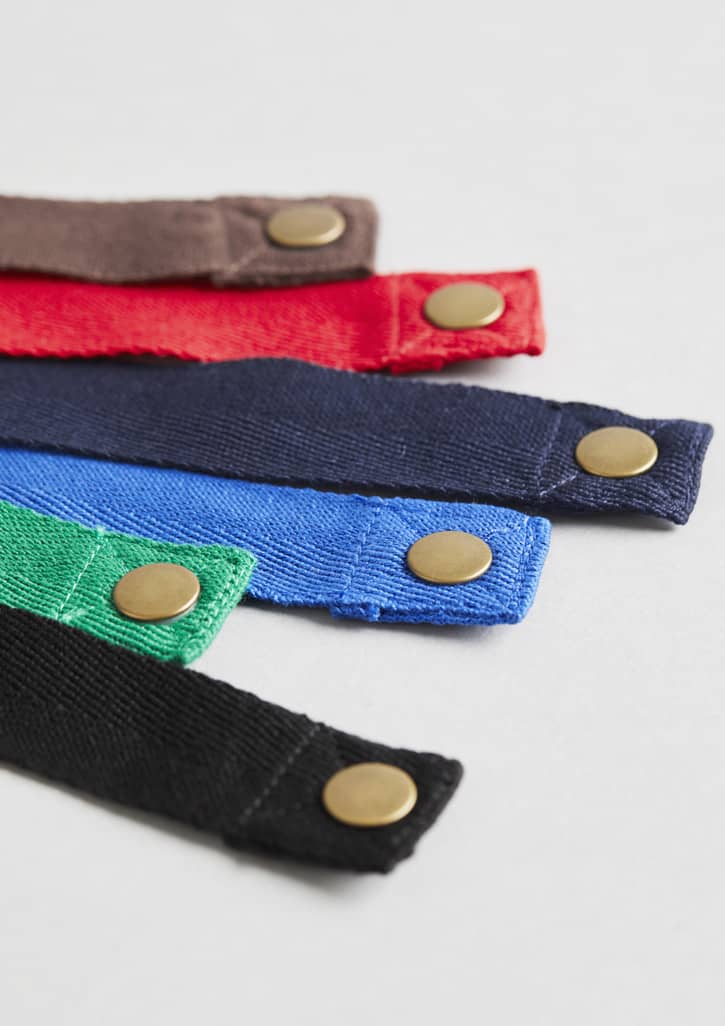 A selection of Urban Bib Straps in red, blue, green, black, and brown, featuring brass snaps. Urban Bib Straps - Image 1