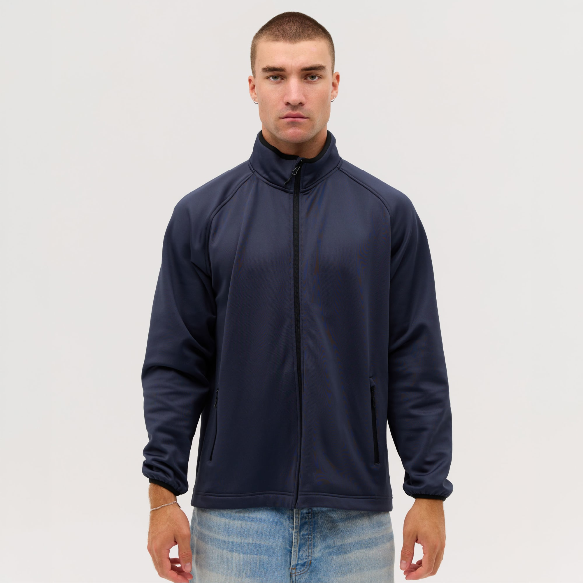 A navy Summit Bonded Jacket on a male model, featuring a zip front and a collar, with a logo. Summit Bonded Jacket - Image 1