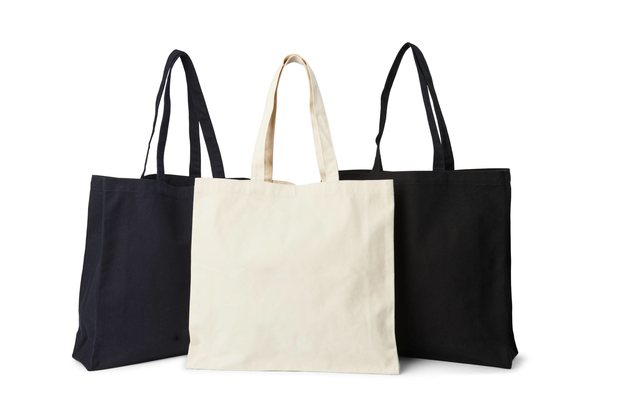 Three tote bags displayed: one black, one cream, and one black, featuring long handles and a simple design. Heavy Tote Bag - Image 1