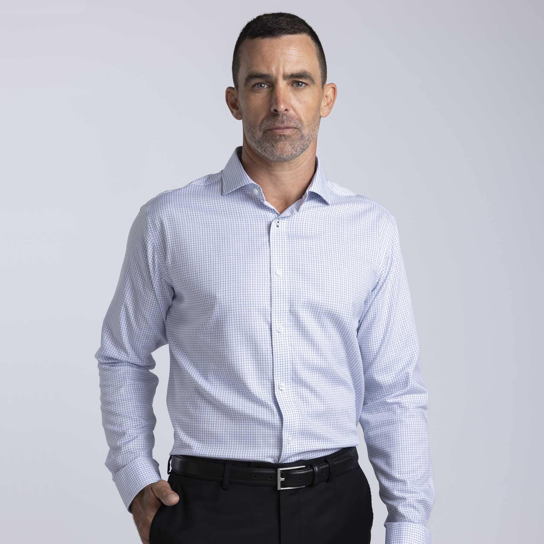 A men's button-up shirt in a blue and white check pattern with a collar and long sleeves. Features a logo. Barkers Corporate Lyndhurst Check Shirt – Mens - Image 1