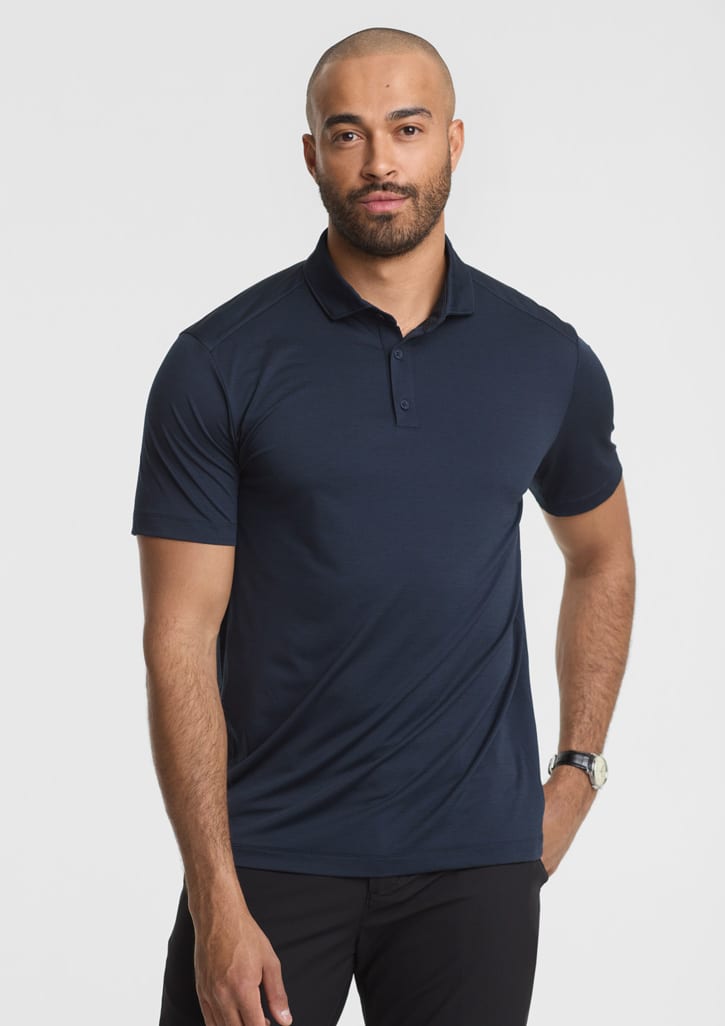 A man stands wearing a navy blue short sleeve polo shirt, featuring a collar and a logo. Mens Phoenix Short Sleeve Polo - Image 1