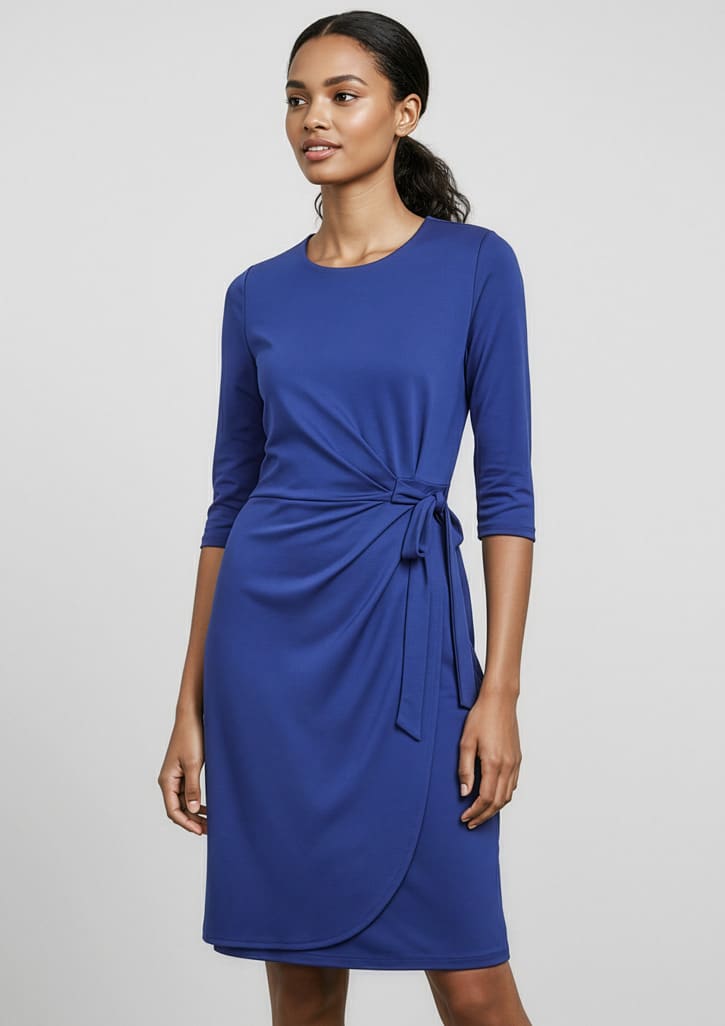 A blue women's dress features three-quarter sleeves and a tied waist detail, set against a neutral background. It has branding. Womens Paris Dress - Image 1