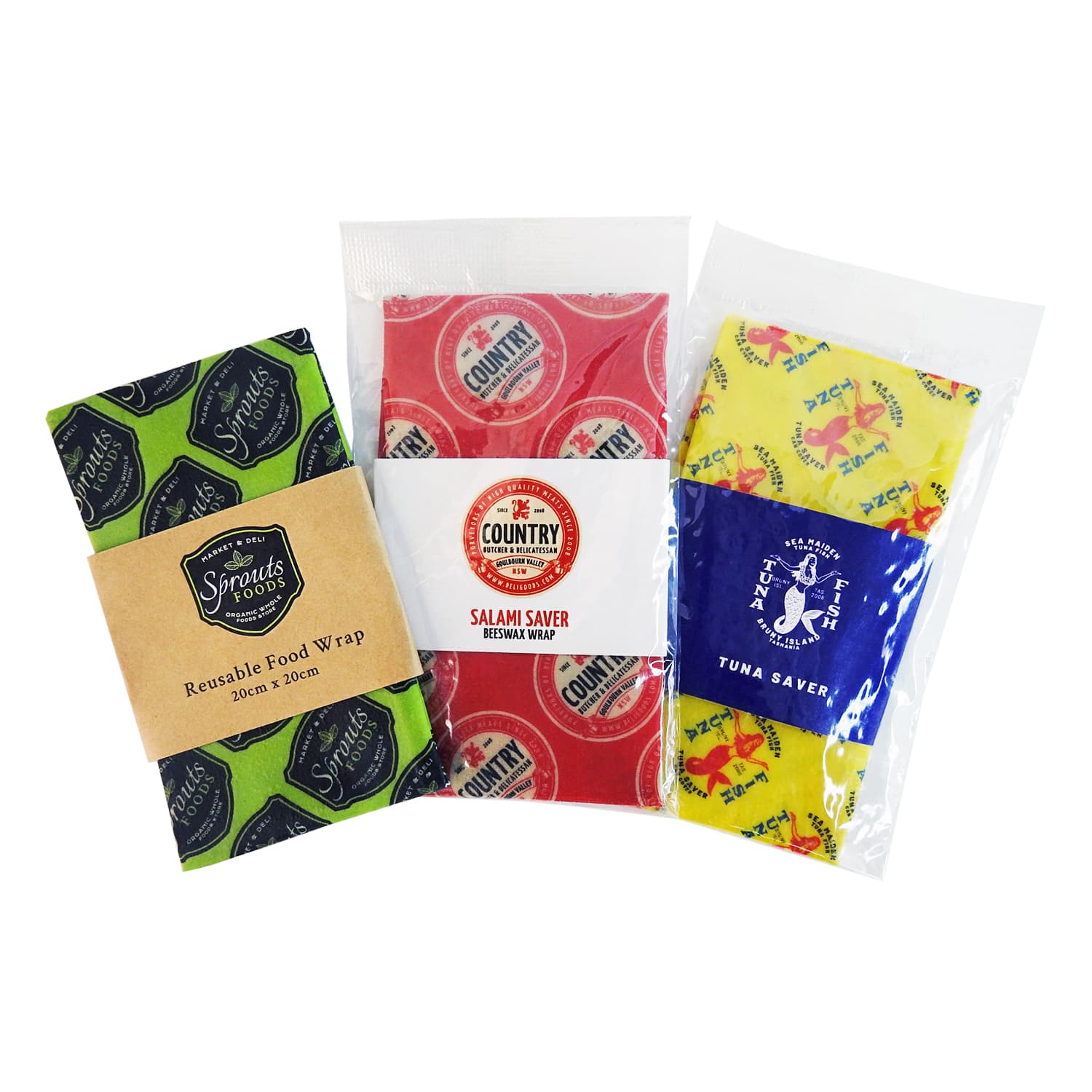 Three beeswax wraps in green, red, and yellow patterns, packaged for reusable food storage. Each features a distinct design and branding. Beeswax Wrap - Image 1