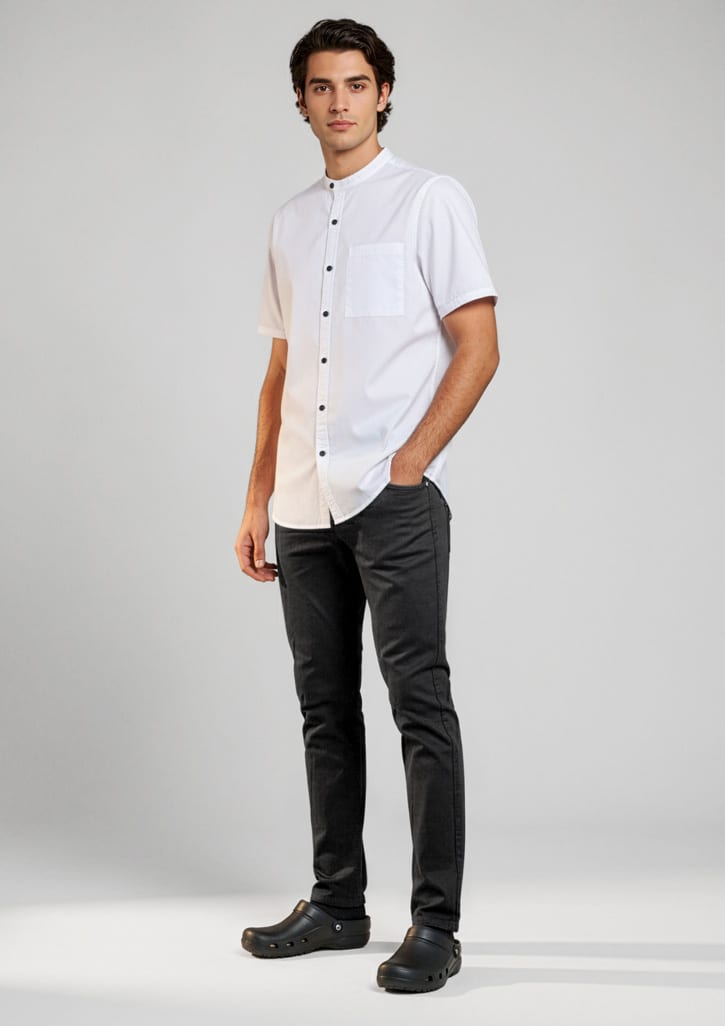 A man stands wearing black chef flex pants paired with a short-sleeve white shirt. The outfit includes a logo. Mens Saffron Chef Flex Pant - Image 1