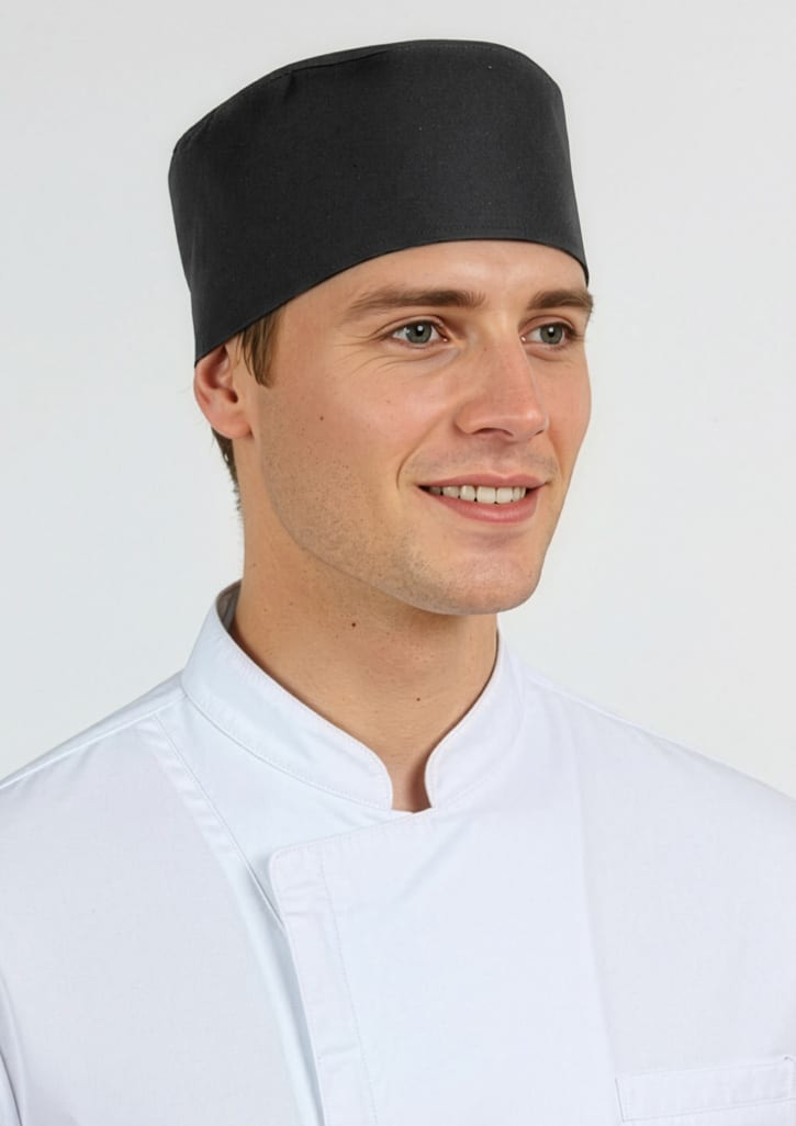 A black mesh flat top hat worn by a smiling male model in a white chef's jacket. The hat features a logo. Mesh Flat Top Hat - Image 1