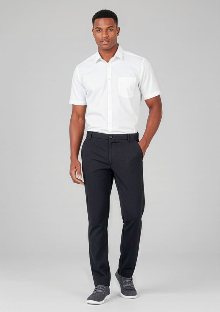 A man in a white shirt and black slacks, standing against a neutral background. The slacks have a flat front and feature a logo. Mens Comfort Waist Flat Front Pant - Image 1