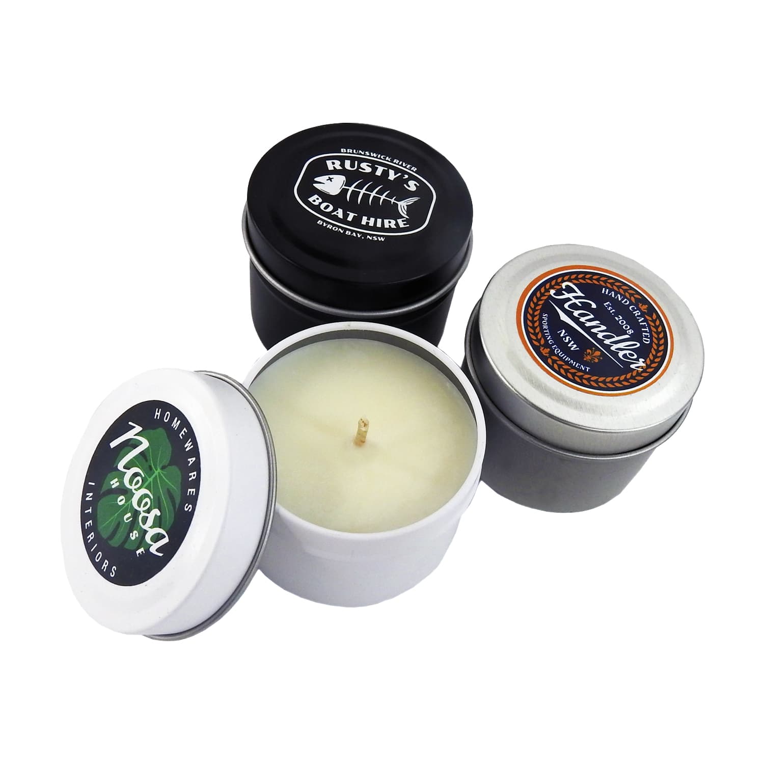 Three small candle tins in black, silver, and white, featuring different designs and a visible wick in the centre of one. Small Candle Tin - Image 1