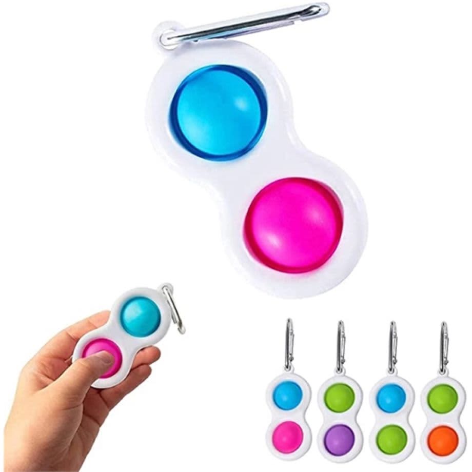 A hand holding a white Dimple Toy keychain featuring blue and pink buttons, with additional keychains in green and orange. Dimple Toy Keychains - Image 1