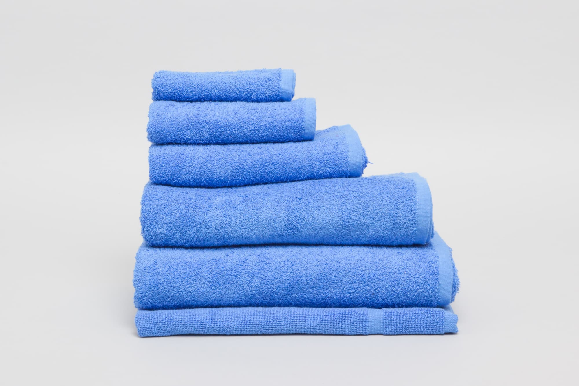 A stack of blue bath towels in varying sizes arranged neatly on a light background. Elite Bath Mat 500 gsm Royal Blue - Image 1