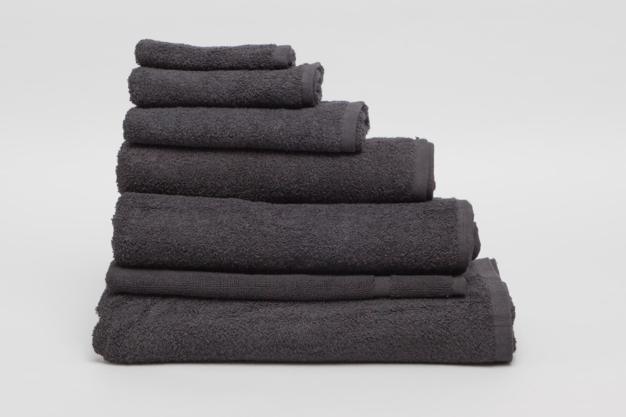 A stack of black towels in various sizes, made from 500 gsm material, featuring a textured finish. Elite Small Hand Towel 500 gsm Black - Image 1