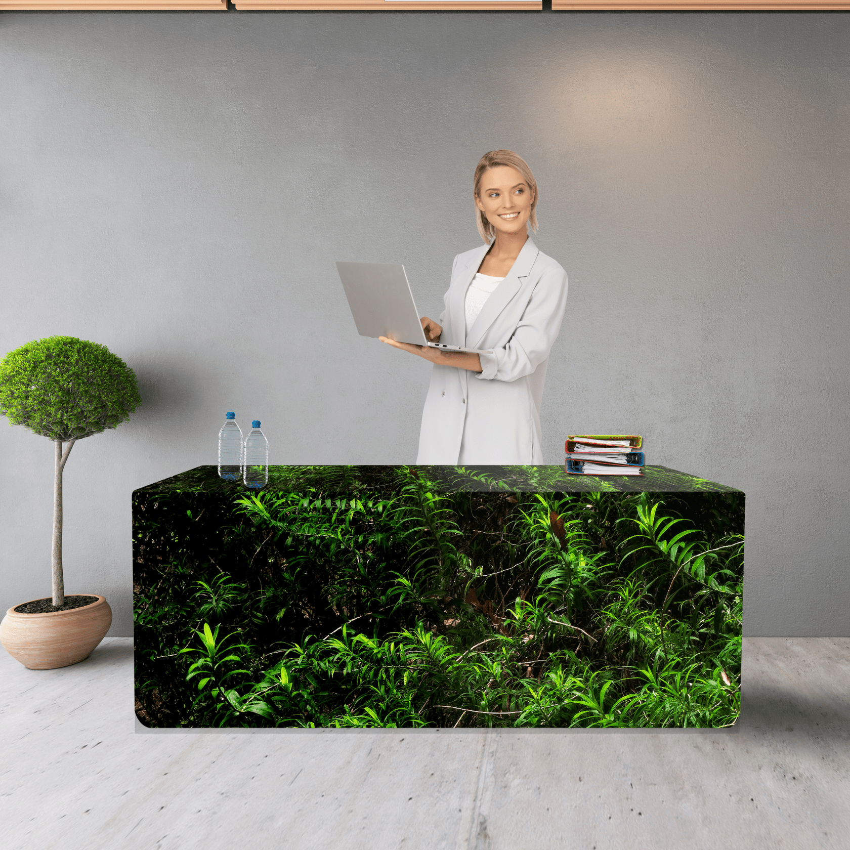 A fitted table cover featuring a green plant design, with a woman holding a laptop standing behind it. rPET Fitted Table Cover 6ft (1800mm) - Image 1