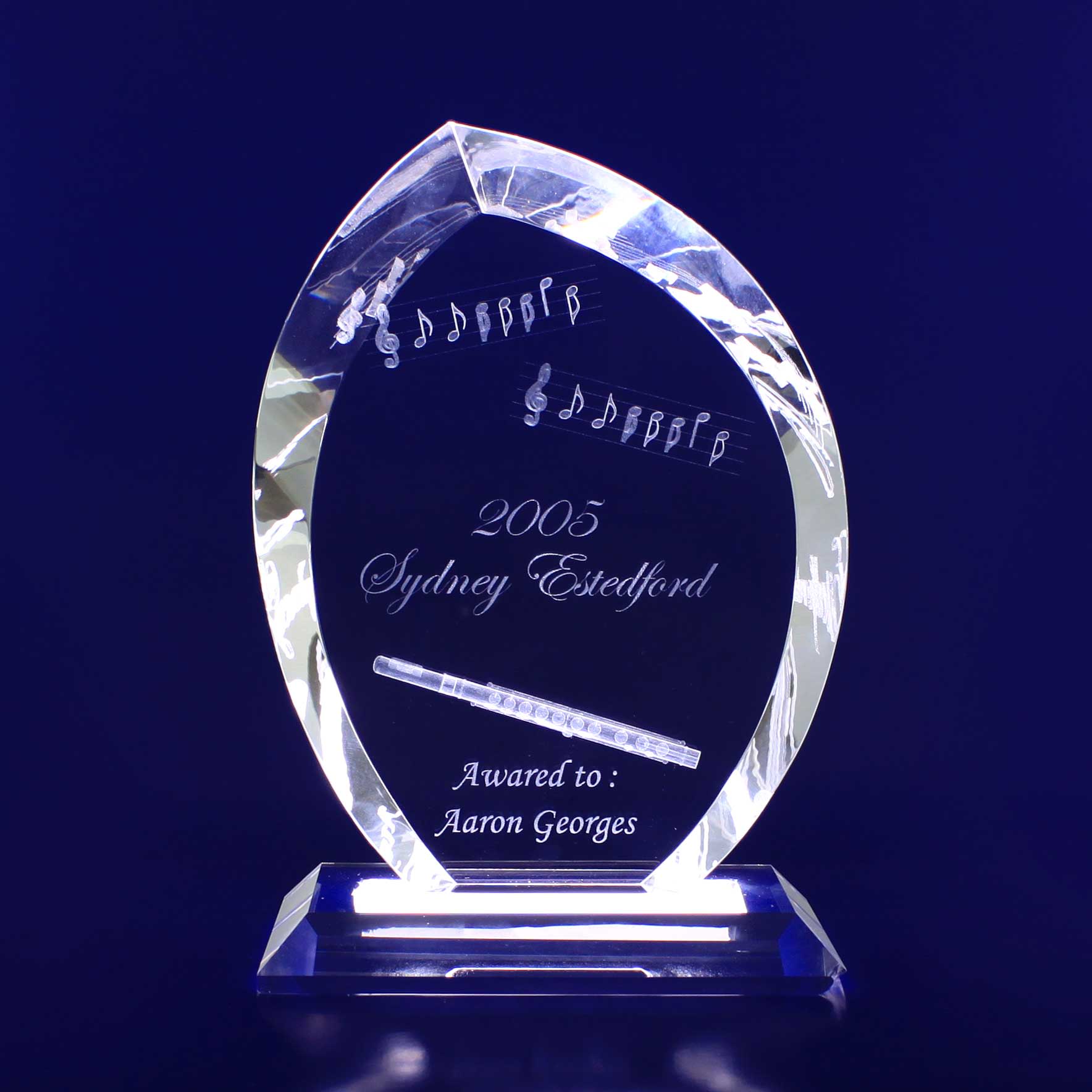 A crystal trophy shaped like a flame, engraved with musical notes and a pen design, on a clear base. 3D Crystal Flame Trophy - Image 1