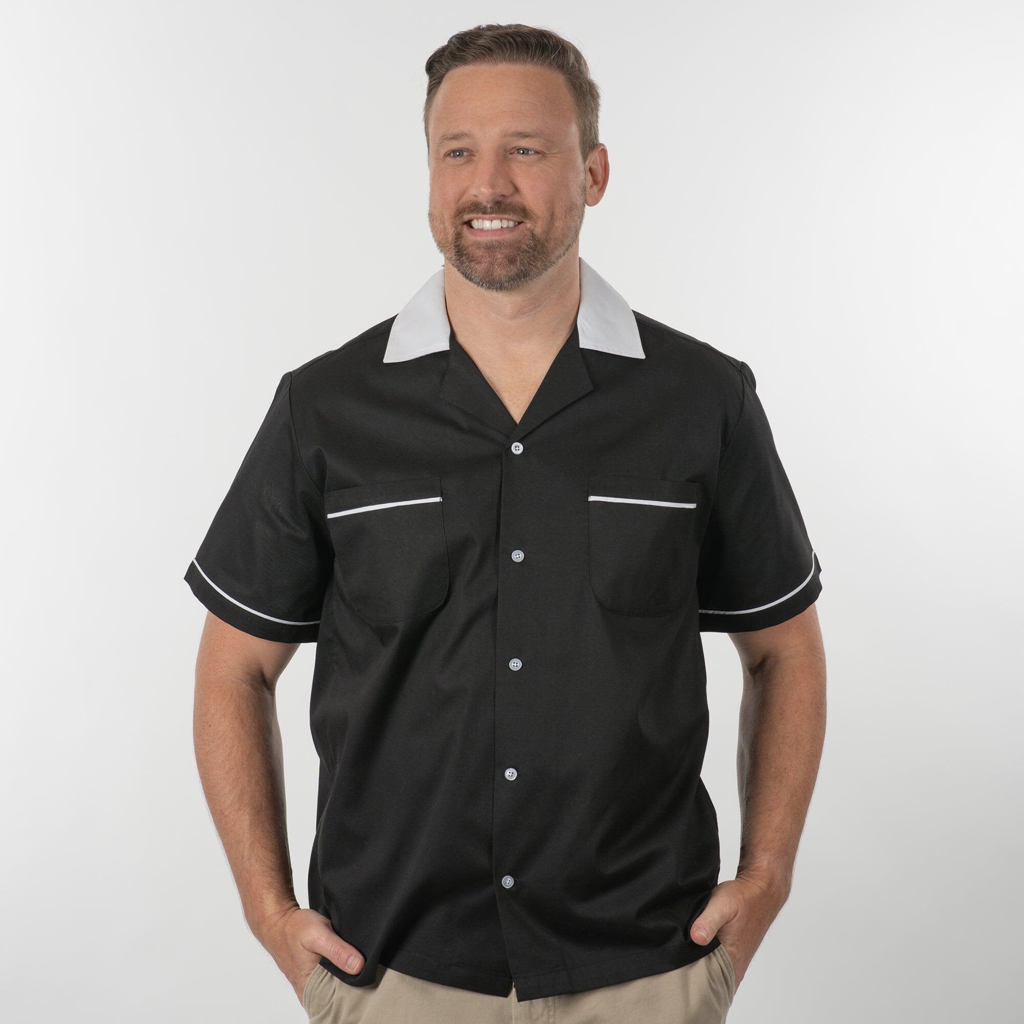 A black button-up shirt with a grey collar, featuring white piping and chest pockets, worn by a model. Hilton GM Legend Bowling Shirt - Image 1