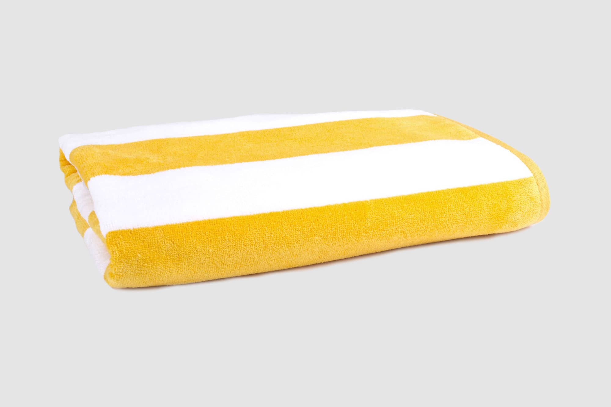 A folded pool towel featuring yellow and white stripes, made from 450 gsm material, with a logo present. Havana Beach & Pool Towel 450 gsm Yellow - Image 1