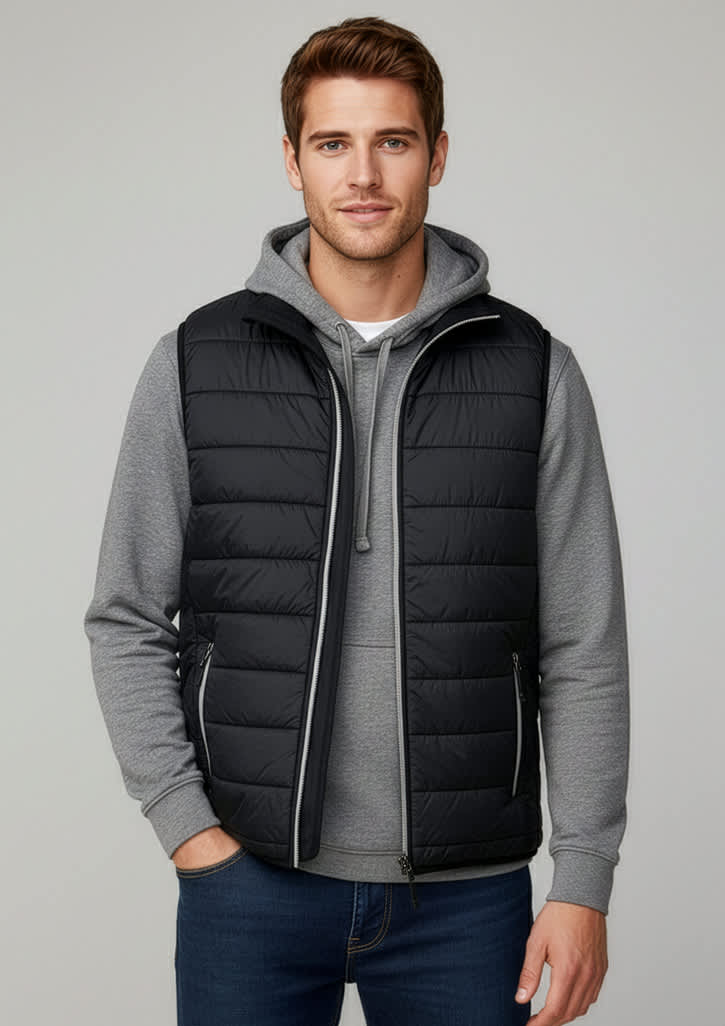 A black puffer vest worn over a grey hoodie, modelled by a man, featuring a zip front and a logo. Mens Stealth Vest - Image 1