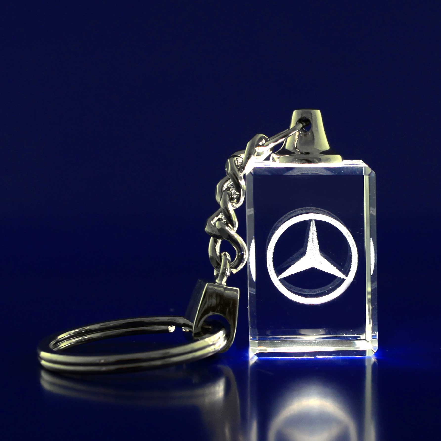 A 3D crystal keyring featuring a silver logo, attached to a metallic chain, on a blue background. 3D Crystal Keyring - Image 1