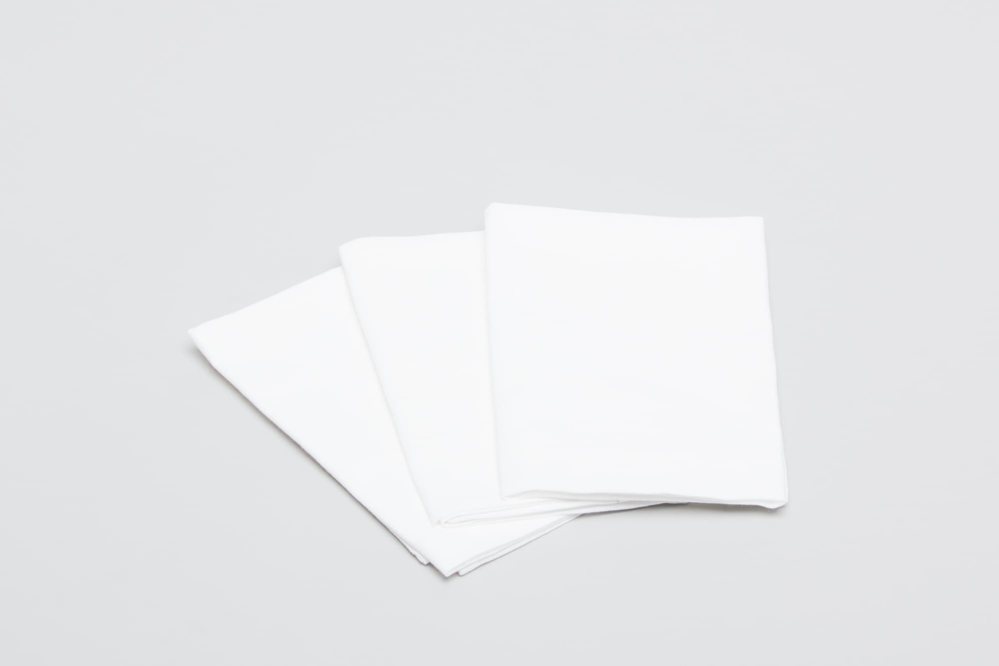 Three white cotton tea towels folded neatly, arranged on a light grey background. One towel has a logo. Cotton Tea Towel White - Image 1