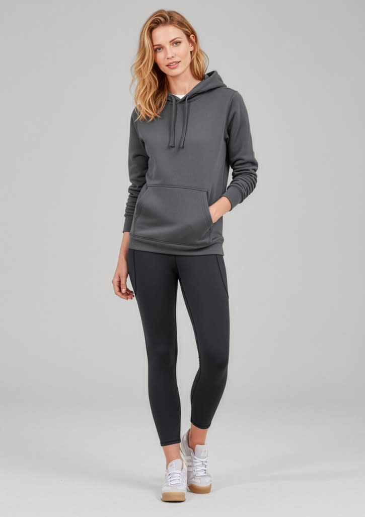 A woman in a grey hoodie poses with black 7/8 length leggings. The outfit includes casual white sneakers. Womens Luna 7/8 Length Legging - Image 1
