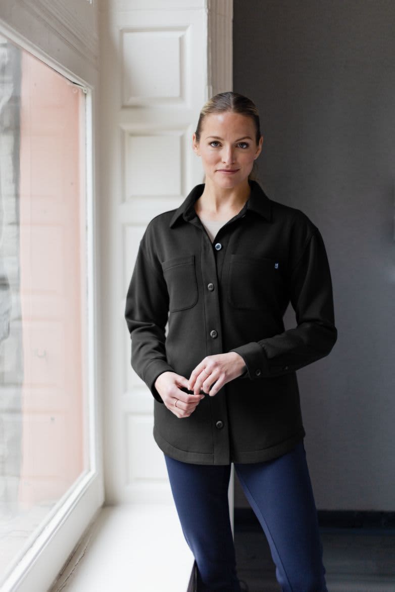A black eco shirt jacket with a button-up front and two chest pockets, worn by a model indoors. Ladies Roam Eco Shirt Jacket - Image 1