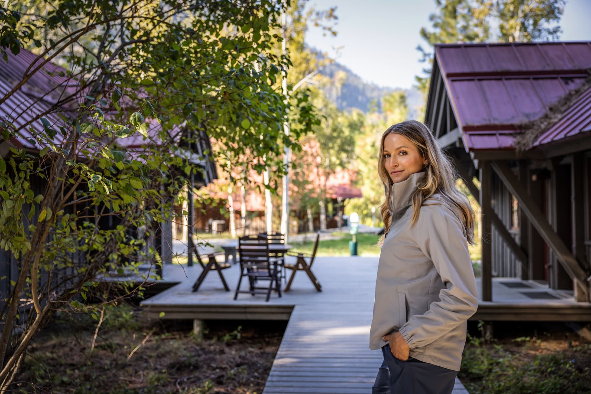 A light grey ladies full zip jacket is worn by a woman standing outdoors, surrounded by cabins and greenery. Ladies Charter Full Zip Jacket - Image 1