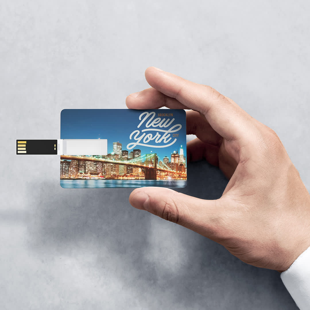 A hand holds a blue USB memory stick featuring a design of New York's skyline. The device has a logo on it. USB Memory Sondy 16GB - Image 1