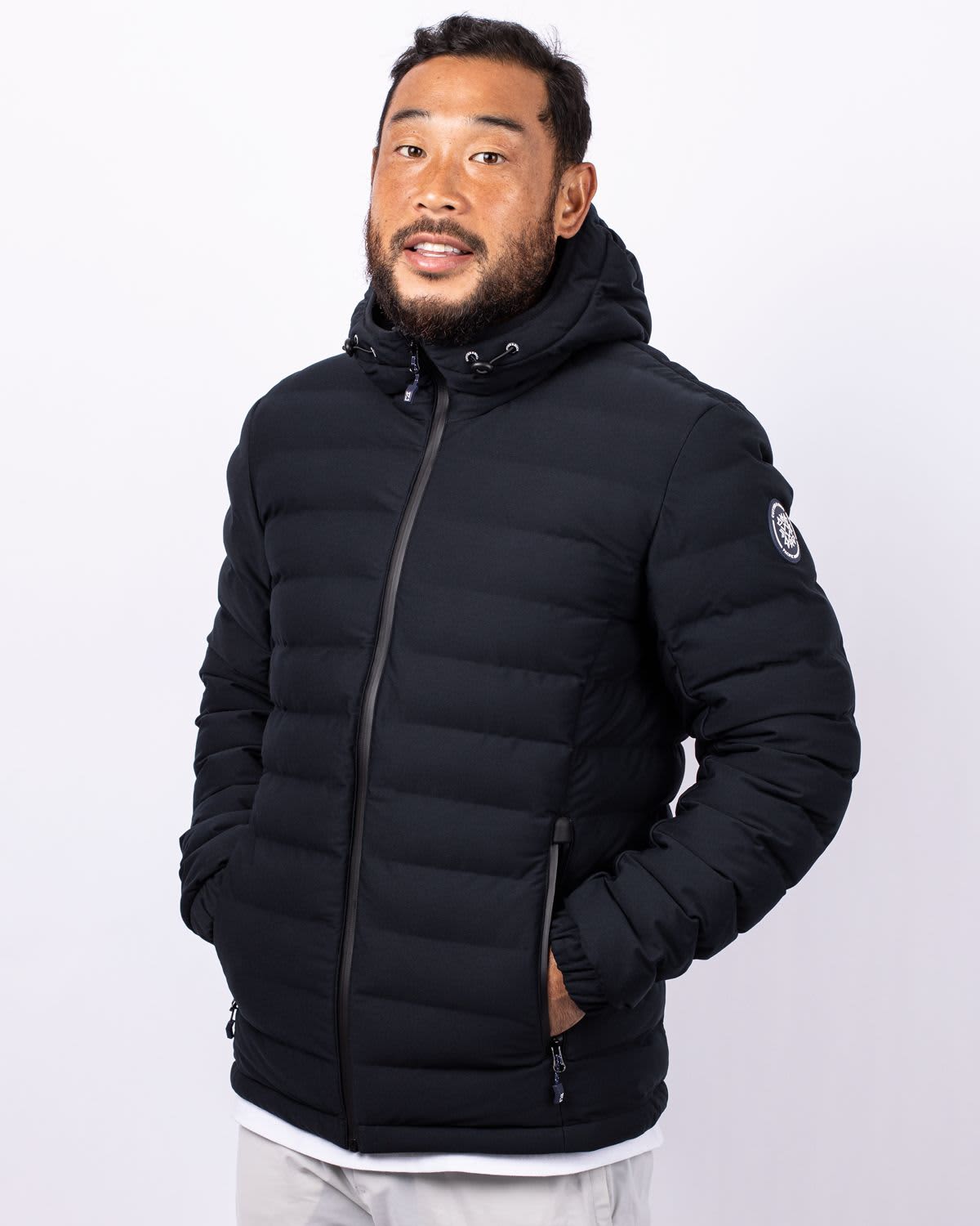 A black men's puffer jacket with a hood, featuring a logo and zippered pockets. Men's Mission Ridge Puffer jacket - Image 1