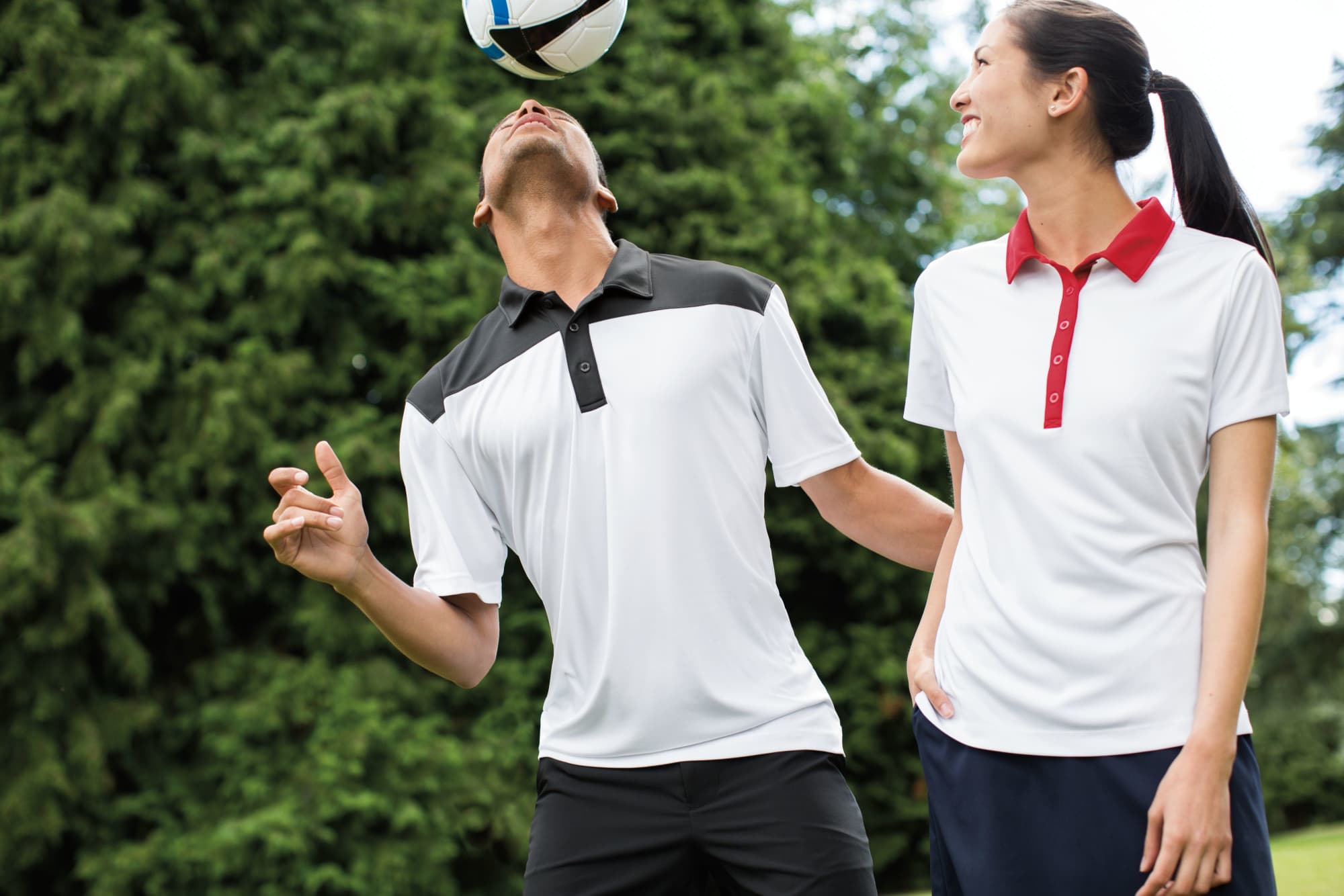 A male and female model wearing men's polo shirts in white with black and red colourblock accents, featuring a logo. Men's Parma Colourblock Polo - Image 1