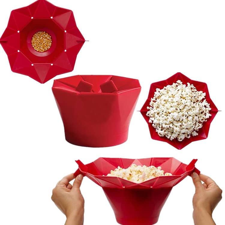 A red popcorn bucket featuring a collapsible design, shown with kernels and popped popcorn. It has a logo. Popcorn Bucket - Image 1