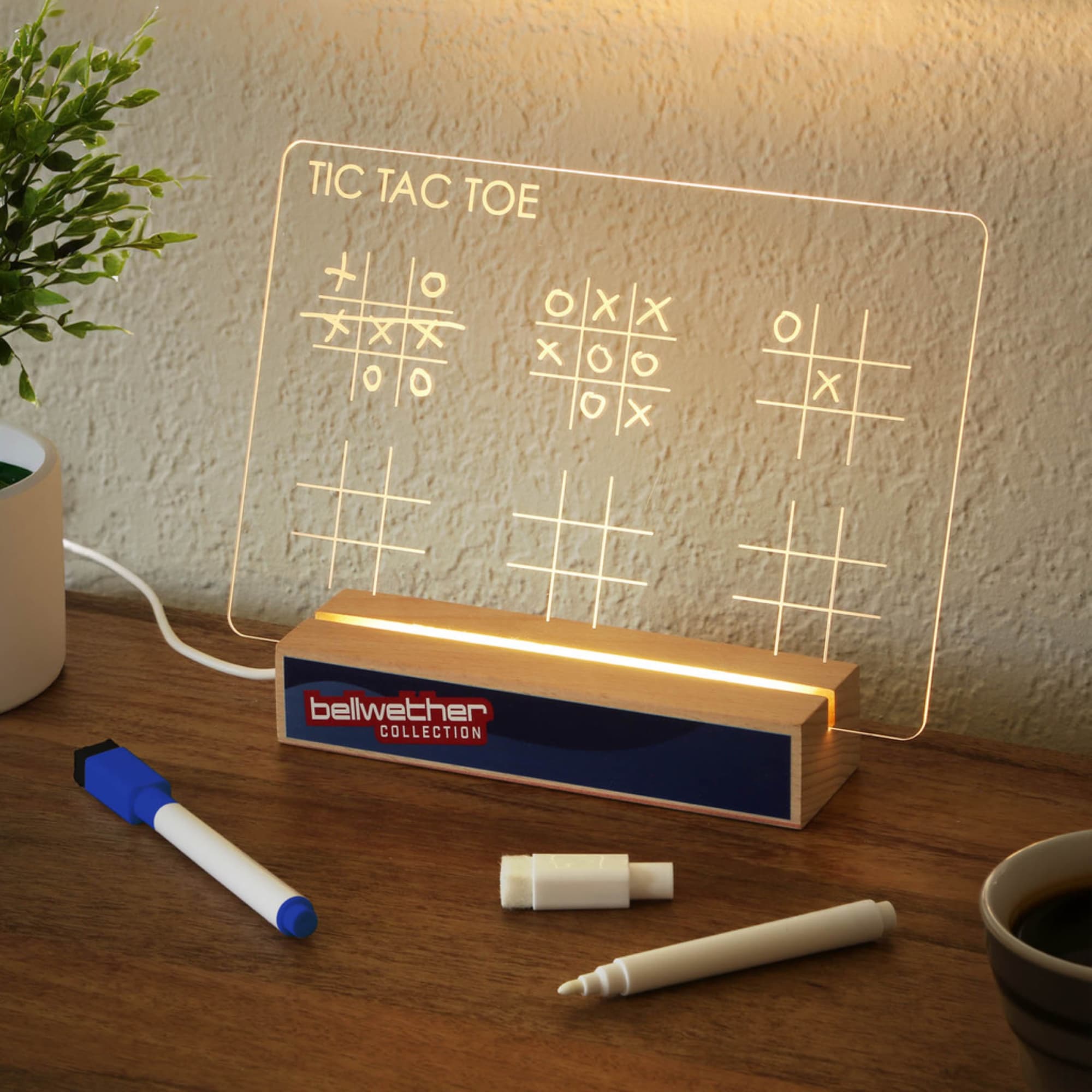 A light-up Tic Tac Toe display featuring a clear panel with game markings and a wooden base in blue and natural colours. Desktop Light Up Set - Image 1