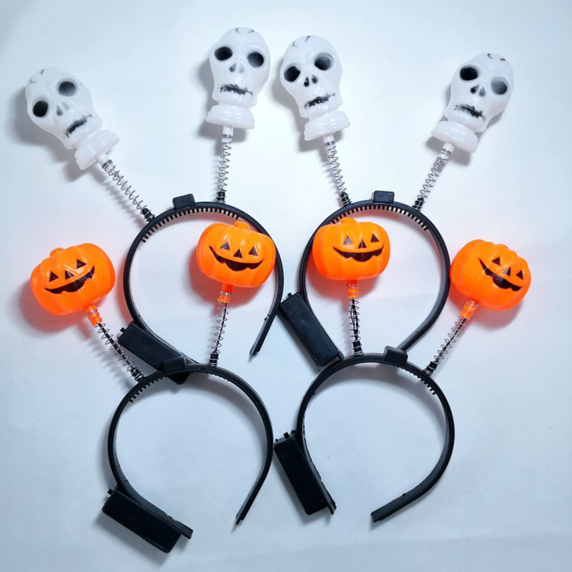 A black headband featuring orange pumpkins and white skulls on springs. Ideal for Halloween celebrations. Flashing Pumpkin LED Headband - Image 1