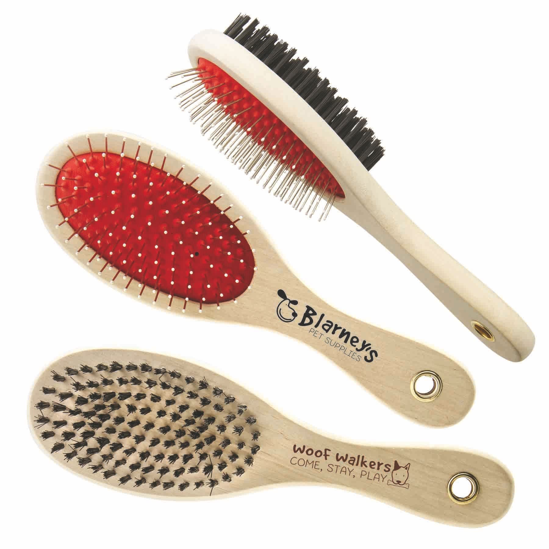 A double-sided pet brush with a red bristle side and a black bristle side, featuring wooden handles and logos. Double Sided Pet Brush - Image 1